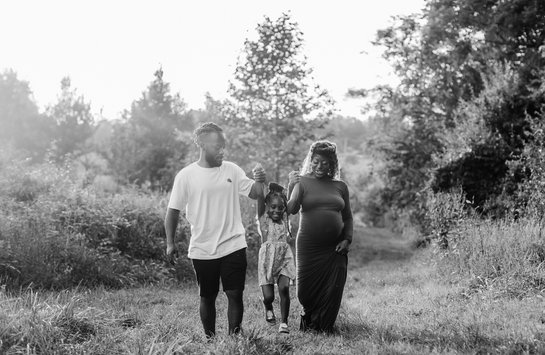 Pregnant Black mom with partner and child in field